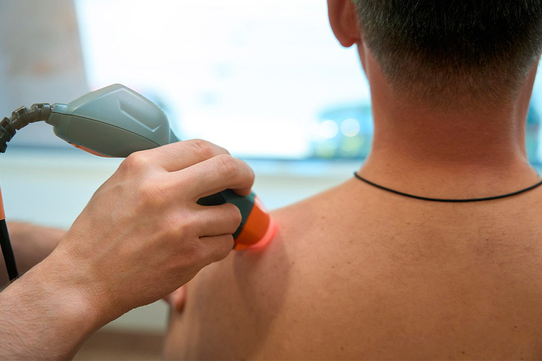 A man employs an infrared device to assess his body temperature, demonstrating its application in physical therapy.