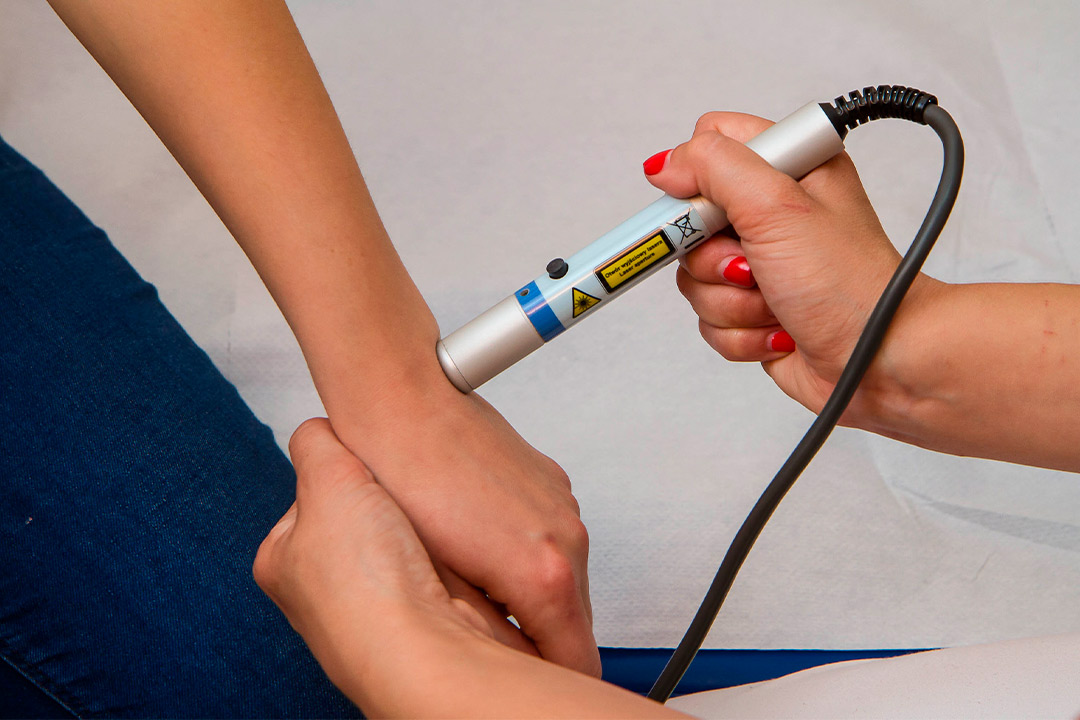 Individual using a Class IV laser device to assess arm measurements for fall treatment purposes.