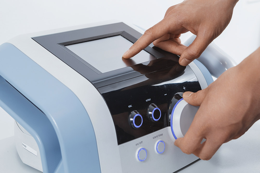 Shockwave therapy machine. A person using a handheld device for skin treatment, highlighting the intersection of technology and personal care.