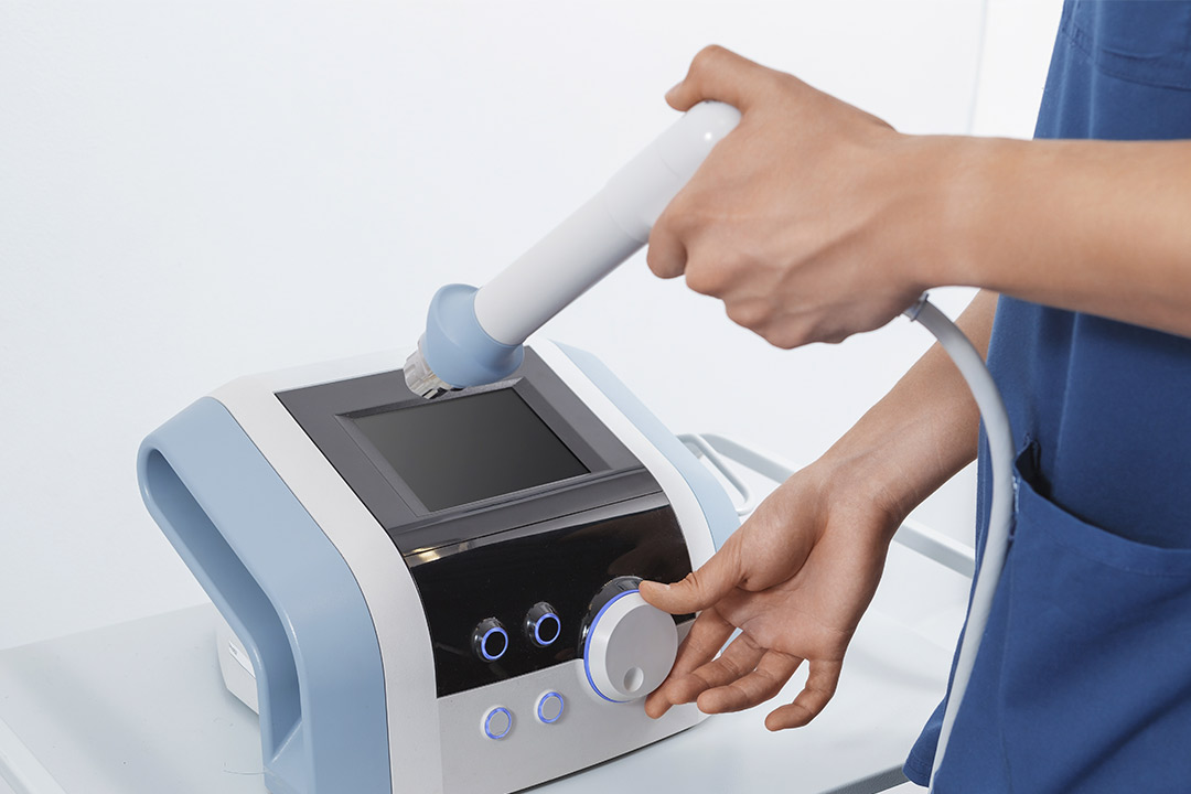 An individual uses a shockwave therapy to clean a surface, showcasing modern cleaning equipment in action.