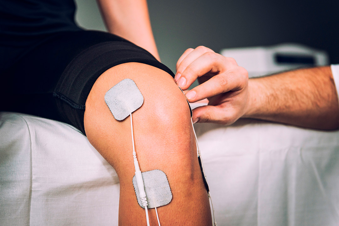 Individual using a PEMF therapy device on their knee, aimed at accelerating healing and alleviating discomfort.