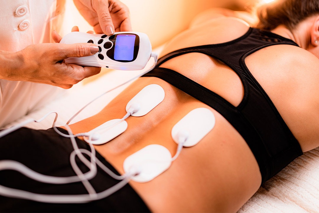 A woman enjoys an electric massage on her back, showcasing PEMF therapy's role in enhancing recovery and wellness.