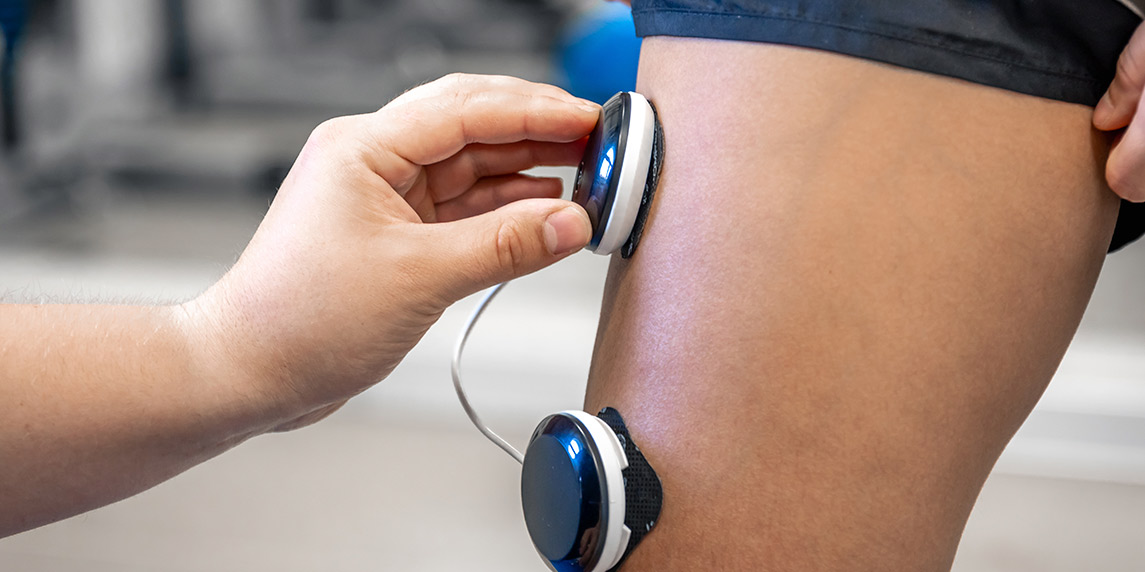 Individual using an electronic device to measure their leg, highlighting the advantages of PEMF therapy.